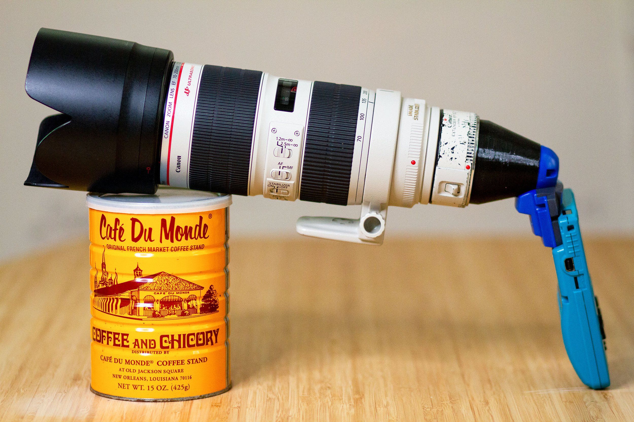 A Canon 70-200mm zoom lens on a blue Game Boy Color, resting on a coffee can