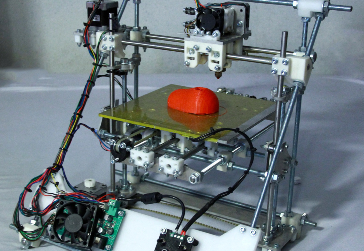 A home 3D printer printing an orange instrument shell